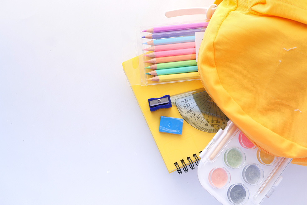 Back to School Concept with Yellow Backpack and School Suppliers on Table